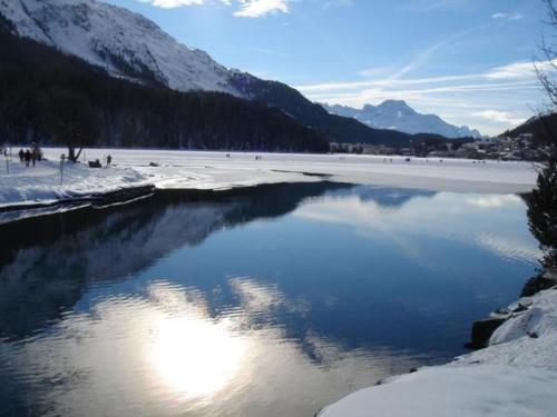 a body of water with snow and mountains at Skyline 214 in St. Moritz