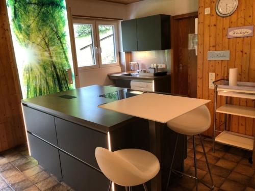 a kitchen with a counter and two stools in it at Chalet BERGglück Willingen - Nähe Skilifte in Willingen
