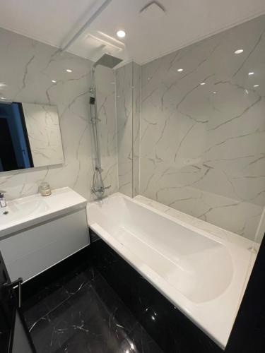 une salle de bain avec une baignoire blanche et un lavabo dans l'établissement Appartement 3 pieces 2 minutes à pied RER vers Paris, à Gagny