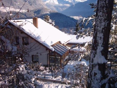 una casa ricoperta di neve con montagne sullo sfondo di Große Ferienwohnung in Imst mit Balkon und Panoramablick auf die Ötztaler und Pitztaler Alpen a Imst