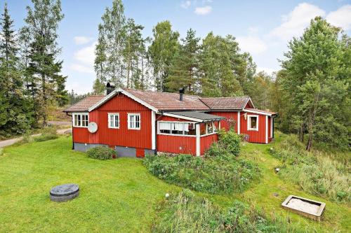 een rood huis midden in een tuin bij Idyllisch gelegenes ebenerdiges Ferienhaus mit Terrasse und Wintergarten mit traumhaften Blick in die Weite der Umgebung in Svenljunga