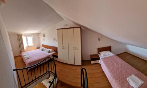a attic room with two beds and a staircase at Vila Lena in Petrovac na Moru