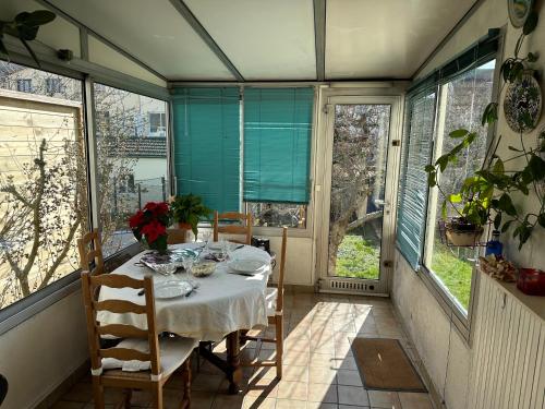 comedor con mesa y algunas ventanas en Villa martin en Antony