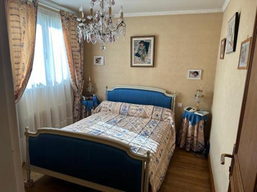 Un dormitorio con una cama azul y una lámpara de araña. en Villa martin en Antony