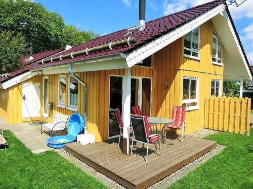 a yellow house with a table and chairs on a deck at Gemütliches Ferienhaus Alissa für 5 Personen mit Sauna und Kaminofen von Privat im Ferienpark Extert in Extertal