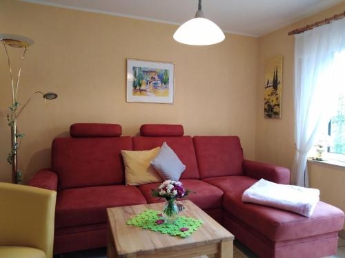 ein Wohnzimmer mit einem roten Sofa und einem Tisch in der Unterkunft Wohnung in Boverath mit Finnischer Sauna in Daun