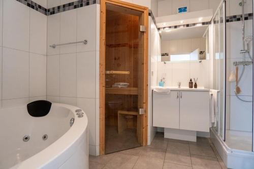 a bathroom with a tub and a shower and a sink at Strandpark-Grossenbrode-Haus-Moewennest-Wohnung-2 in Großenbrode
