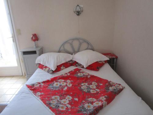 a bed with a red blanket and two pillows at la maisonnette du peu-morier in Vouvray