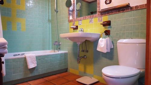 La salle de bains est pourvue d'un lavabo, de toilettes et d'une baignoire. dans l'établissement Wunderschönes Ferienhaus in La Sorrueda mit Terrasse, Whirlpool und Grill, à La Sorrueda