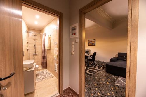 y baño con ducha, lavabo y sofá. en STAMOS Apartment airport en Spáta