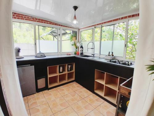 a kitchen with a black counter top and windows at The Secret Motel 7 Salazie à 15 min d'hell bourg in Salazie