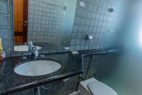 a bathroom with a sink and a mirror and a toilet at Hotel Praia dos Carneiros in Tamandaré