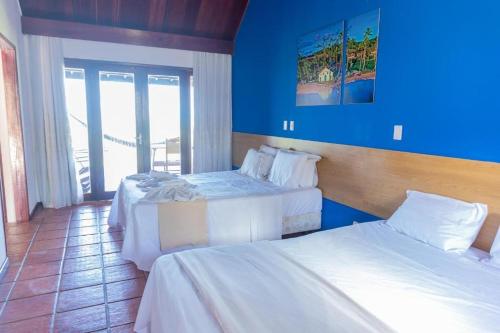 a hotel room with two beds and a blue wall at Hotel Praia dos Carneiros in Tamandaré
