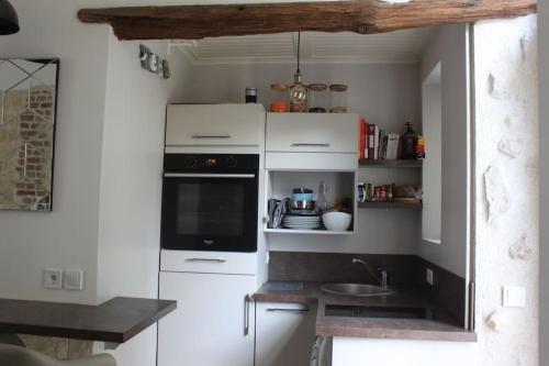 una piccola cucina con armadi bianchi e lavandino di Studio centre-ville Rueil-Malmaison - proche RER A a Rueil-Malmaison