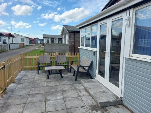 a patio with two benches and a house at 'New Memories' Dog Friendly Holiday Chalet in Bridlington