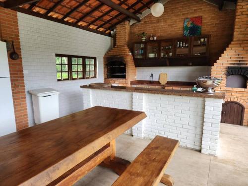 a large kitchen with a wooden table and a counter at Chácara dos Sonhos com Piscina e Hidromassagem in Cotia
