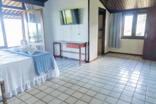 a bedroom with a bed and a desk in a room at Hotel Praia dos Carneiros in Tamandaré
