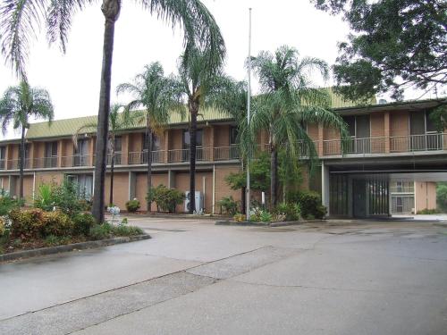 a large building with a palm tree in front of it at John Hunter Motel Muswellbrook in Muswellbrook