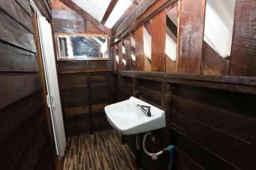 La salle de bains en bois est pourvue d'un lavabo blanc. dans l'établissement Green Feel Farmstay, à San Sai