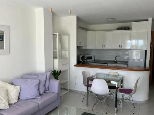 een woonkamer met een paarse bank en een tafel bij Zee zicht apartement Altea 2 pers in Caserío Capnegret