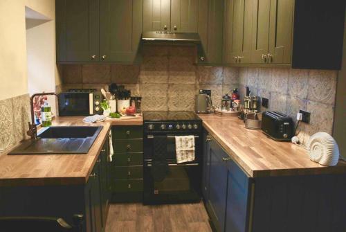 a kitchen with green cabinets and a counter top at Holmlea Cottage in Moffat