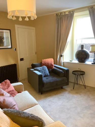a living room with a couch and a window at Holmlea Cottage in Moffat