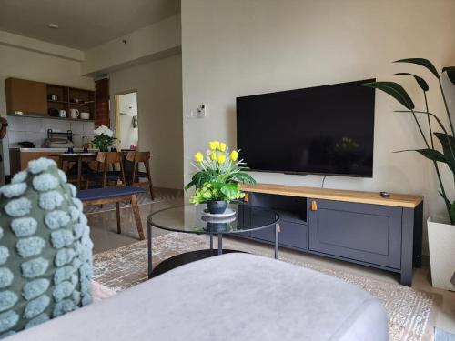 ein Wohnzimmer mit einem TV und einem Tisch mit Blumen in der Unterkunft Comfy Stay in Kampong Baru Subang