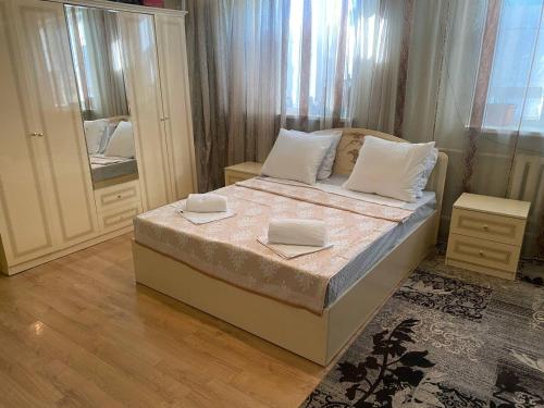 Schlafzimmer mit einem Bett mit weißen Kissen und einem Spiegel in der Unterkunft The Silk Road Stopover in Kazarman