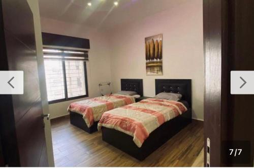 a bedroom with two beds and a window at AMT in Amman