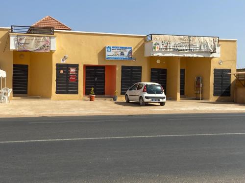 um carro branco estacionado em frente a um edifício em Résidence Daldiam em Thiès