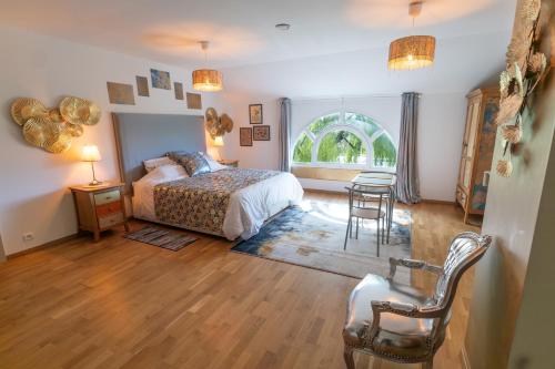 a bedroom with a bed and a table and chairs at Chez PhiL in La Pomarède