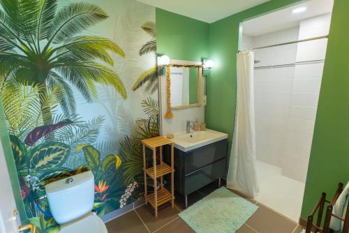 a bathroom with a palm tree mural on the wall at Chez PhiL in La Pomarède