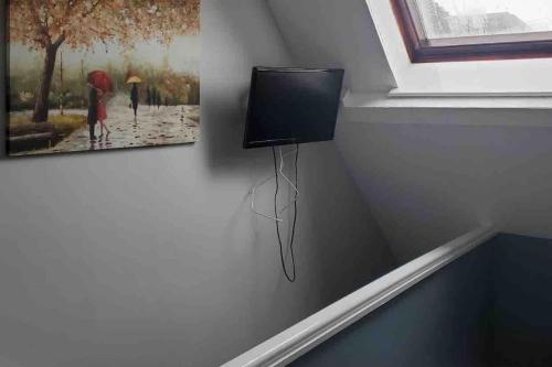 a tv on a wall with a picture of two people with umbrellas at Tiny one bedroom house in Mablethorpe