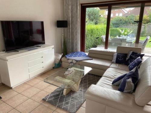 un salon avec un canapé et une télévision à écran plat dans l'établissement "Moin Moin" - gemütliches Ferienhaus mit Garten und Terrasse für die große Familie, à Grömitz
