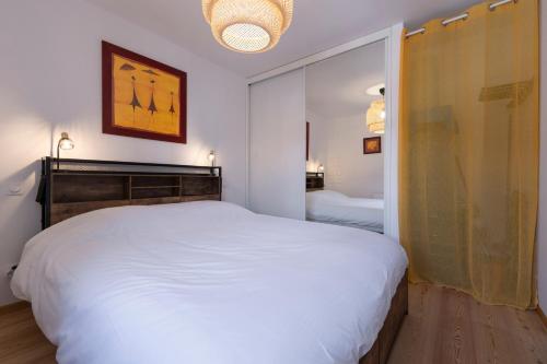 a bedroom with a large white bed and a mirror at Petite Anita - Centre ville - Parking privé in Barcelonnette