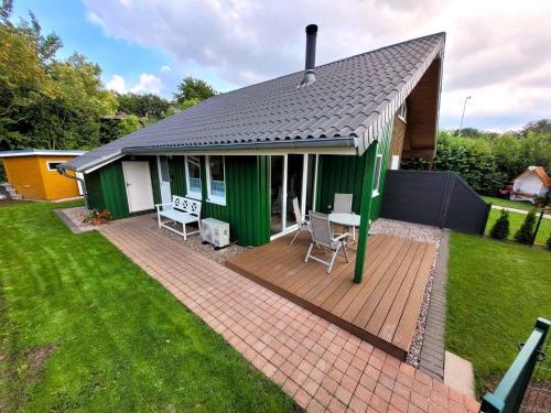 ein grünes und weißes Haus mit einer Terrasse in der Unterkunft Ferienhaus Luna mit Saunahaus, Kaminofen, Klimaanlage, schöner Blick im Ferienpark Extertal in Extertal