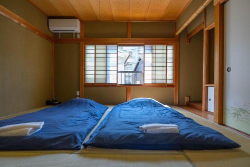京都美筑粟田的窗户客房内的一张蓝色大床