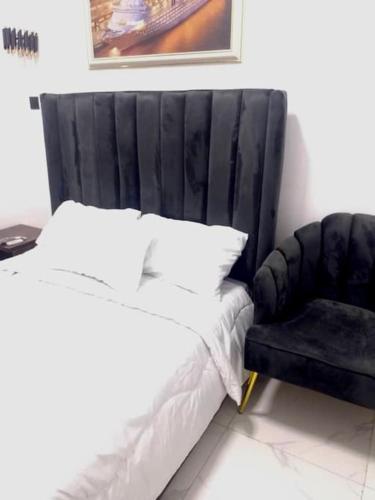 a bed with a black headboard and a black chair at Luxury House In Lekki Lagos in Ikota