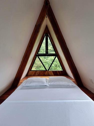 a white bed in a room with a window at Camiguin Volcano Houses - A-Frame house in Mambajao