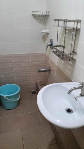 a bathroom with a white sink and a blue bucket at Grandiose Domicile in Basak