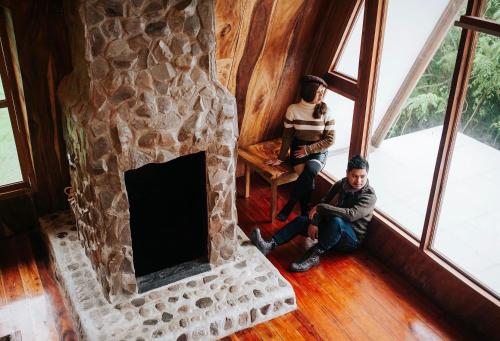 two people sitting in a room with a fireplace at Camiguin Volcano Houses - A-Frame house in Mambajao