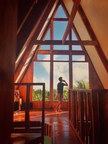 a man walking in front of a large window at Camiguin Volcano Houses - A-Frame house in Mambajao