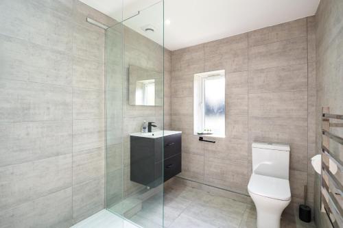 a bathroom with a toilet and a glass shower at The White Cottage at Gildridge + Private Hot Tub+EV in Chiddingly