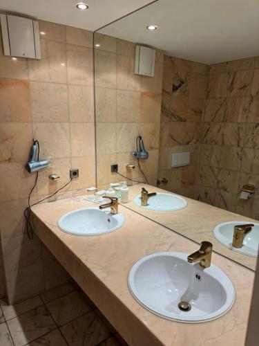 a bathroom with three sinks and a large mirror at Hotel Seeschau in Reichenau