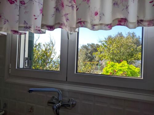 two windows with curtains in a bathroom with a sink at Efi's apartment in Apróvaton