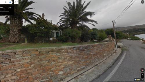 a stone wall next to a street with a palm tree at Efi's apartment in Apróvaton