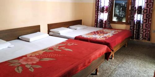 two beds in a room with red and white sheets at Hotel Gayatri Guest House Haridwar Near Railway Station - Ganga Ghat - Best Hotel in Haridwar in Haridwār