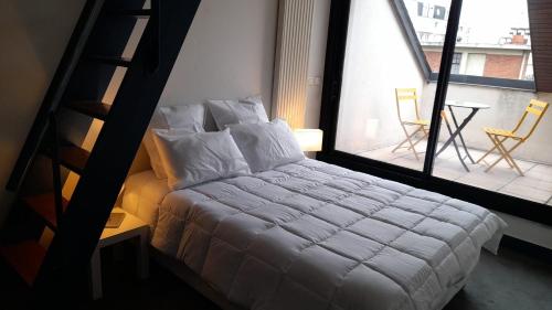 a bedroom with a bed with a ladder and a balcony at triplex, centre-ville, terrasse in Nogent-sur-Marne