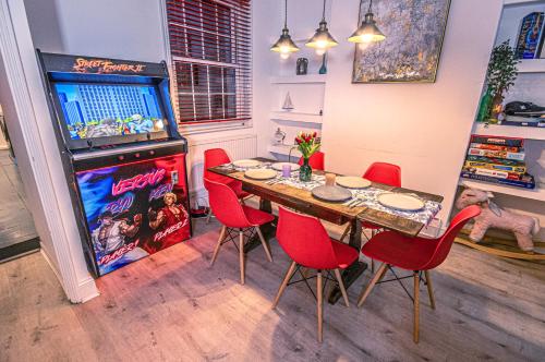 un comedor con mesa, sillas rojas y un videojuego en Central 3 - Bedroom Townhouse in Brighton with Parking, en Brighton & Hove
