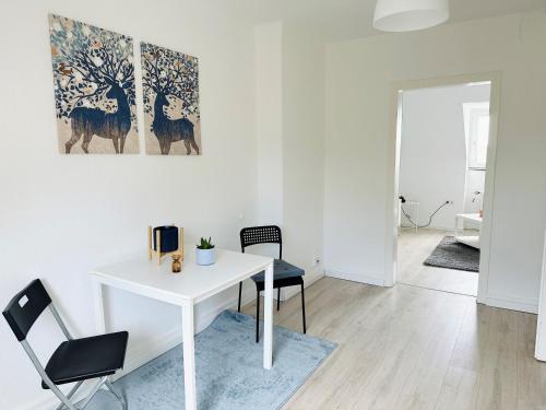uma mesa branca e cadeiras num quarto branco em Möbliertes Apartment in Bochum-nahe Jahrhunderthalle em Bochum